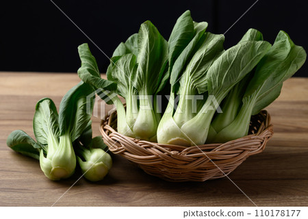 Bok choy or Pak choi (Chinese cabbage) in basket on wooden table with black background Bok choy or Pak choi (Chinese cabbage) in basket on wooden table with black background 110178177