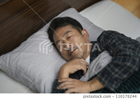 A man in his 50s sleeping in bed 110178244