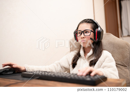A girl wearing headphones and operating a computer A girl wearing headphones and operating a computer 110179002