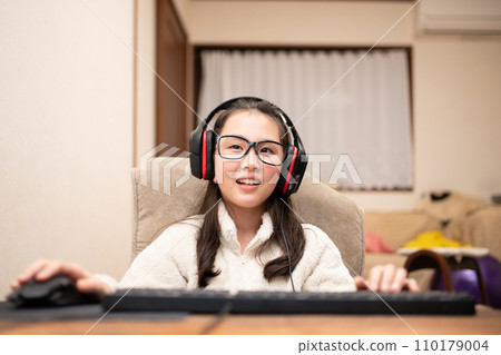 A girl wearing headphones and operating a computer A girl wearing headphones and operating a computer 110179004