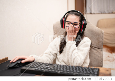 A girl wearing headphones and operating a computer 110179005