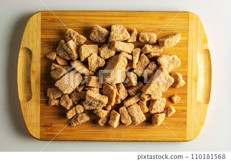 Background of brown unrefined sugar. Healthy food concept. Cane sugar on a wooden cutting board background 110181568