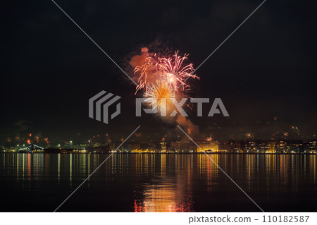 Series of fireworks above large residential area landscape at night. New Years Eve pyrotechnics at Thessaloniki, Greece seen from the city waterfront. 110182587