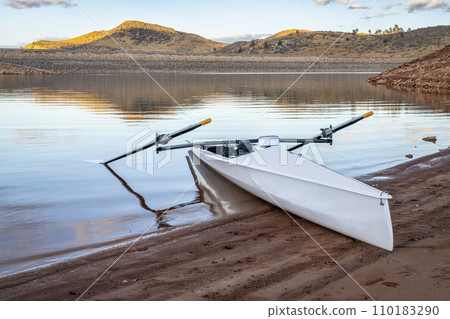 Coastal rowing shell on a shore of Horsetooth Reservoir in fall or winter scenery with a low water level. 110183290