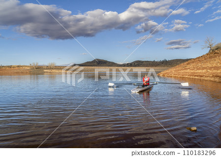 Senior male rower is rowing a coastal rowing shell - Horsetooth Reservoir in fall or winter scenery in northern Colorado. 110183296