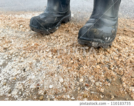 Standing with rubber boots on a sandy road with salt 110183735