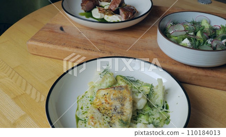 Table setting. Ready-made dishes, meat, fish and vegetable salad on the table, close-up of a dish from a restaurant, three plates with appetizing food. Healthy food. Nutrition concept 110184013