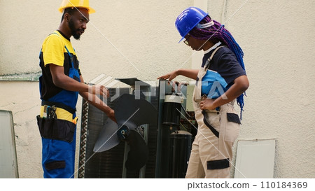 Proficient worker and capable electrician opening up old damaged hvac system to replace it with new performant outdoor air conditioner after draining freon and replacing ductwork Proficient worker and capable electrician opening up old damaged hvac system to replace it with new performant outdoor air conditioner after draining freon and replacing ductwork 110184369