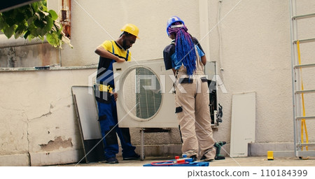 Licensed expert commissioned by client to work on out of order air conditioner, dismantling condenser metal coil panel. Precise wireman opening hvac system to check for bad wiring 110184399