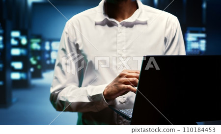 Supervisor walking between rackmounts in high performance computing server room, ensuring faultless operations conditions. Programmer monitoring data center devices energy consumption, close up Supervisor walking between rackmounts in high performance computing server room, ensuring faultless operations conditions. Programmer monitoring data center devices energy consumption, close up 110184453