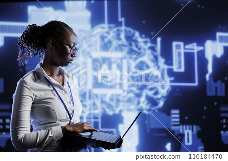 Tech support uses laptop to develop artificial intelligence neural networks nodes modeled after human brain. Data center worker setting up AI machine learning accurately making predictions using data Tech support uses laptop to develop artificial intelligence neural networks nodes modeled after human brain. Data center worker setting up AI machine learning accurately making predictions using data 110184470