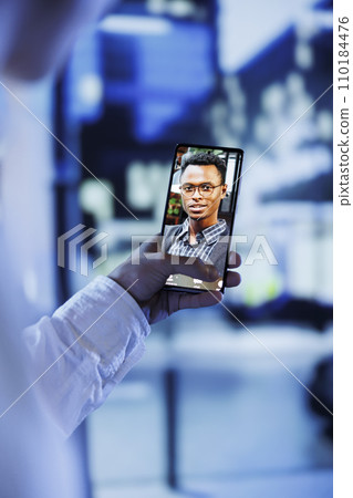 Woman in online videocall with husband while walking around city streets at night, close up. Citizen using phone for remote connection with spouse, showing him surroundings in urban center Woman in online videocall with husband while walking around city streets at night, close up. Citizen using phone for remote connection with spouse, showing him surroundings in urban center 110184476
