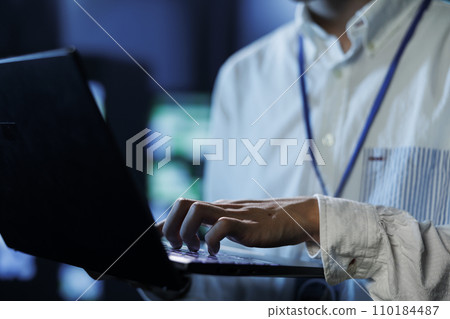 Man between server hub rows providing processing resources for businesses worldwide, blurry background. Scientist fixing data center mainframes tasked with managing massive databases, close up Man between server hub rows providing processing resources for businesses worldwide, blurry background. Scientist fixing data center mainframes tasked with managing massive databases, close up 110184487