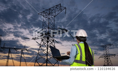Engineer controls information on laptop walking to power transmission lines Engineer controls information on laptop walking to power transmission lines 110184616