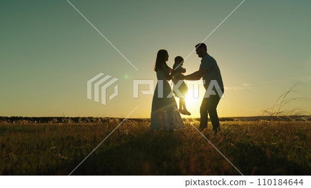 Parents and child playing father spins daughter and gives kid to mother hugs Parents and child playing father spins daughter and gives kid to mother hugs 110184644