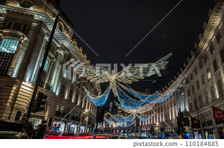 Flying angel Christmas decoration led lights display. Dramatic view of the traditional Christmas decoration lights hanging above Regent Street during dusk. Flying angel Christmas decoration led lights display. Dramatic view of the traditional Christmas decoration lights hanging above Regent Street during dusk. 110184885