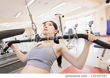 Young woman using lat pulldown Young woman using lat pulldown 110185567