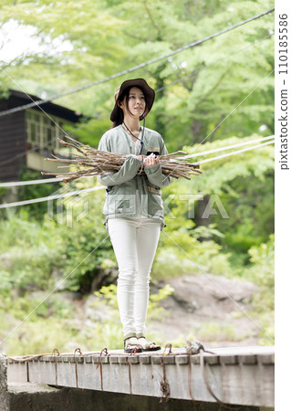 一名婦女在營地裡搬運木柴(樹枝) 一名婦女在營地裡搬運木柴(樹枝) 110185586