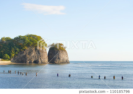 北海道網走市的二津岩和清晨陽光照射下的海裡釣魚的人們 北海道網走市的二津岩和清晨陽光照射下的海裡釣魚的人們 110185796