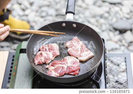 A man grilling pork at a camp gas stove 110185871