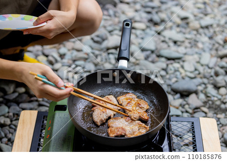 A man grilling pork at a camp gas stove 110185876