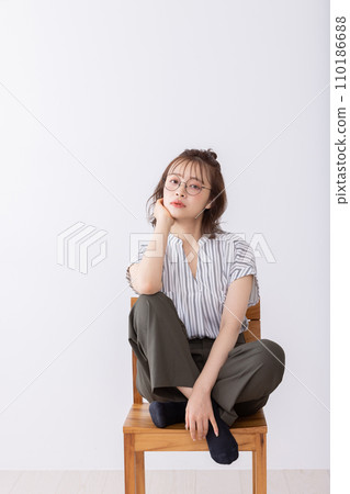 A young woman sitting on a chair A young woman sitting on a chair 110186688
