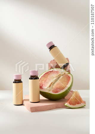 Scene for advertising and branding product with ingredient from pomelo. Front view of medicine bottles with pomelo slices displayed on pink bricks on white background Scene for advertising and branding product with ingredient from pomelo. Front view of medicine bottles with pomelo slices displayed on pink bricks on white background 110187507