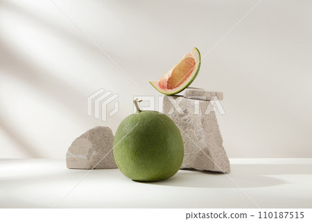 Front view of fresh pomelo and pomelo slice decorated with blocks of gray stone on a white background. Advertising photo with minimal concept. Tropical fruit good for health Front view of fresh pomelo and pomelo slice decorated with blocks of gray stone on a white background. Advertising photo with minimal concept. Tropical fruit good for health 110187515