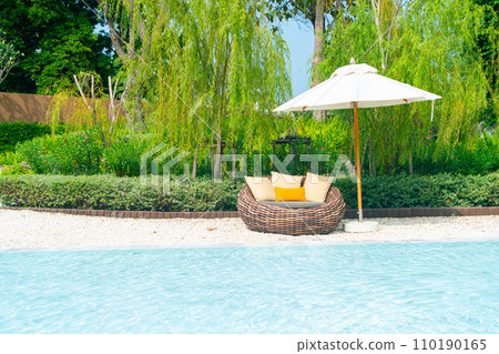outdoor patio chair with pillow and umbrella around swimming pool 110190165
