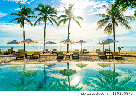 Beautiful luxury umbrella and chair around outdoor swimming pool in hotel and resort with coconut palm tree on blue sky 110190876