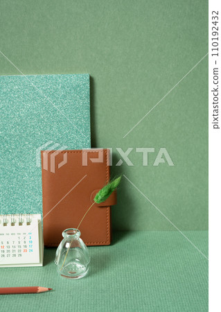Diary notebook, calendar, vase of plant, colored pencil on desk. green wall background. planning office supply Diary notebook, calendar, vase of plant, colored pencil on desk. green wall background. planning office supply 110192432