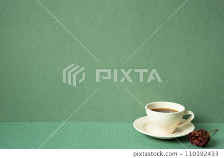 Cup of coffee with dry rose on table. green wall background. copy space Cup of coffee with dry rose on table. green wall background. copy space 110192433