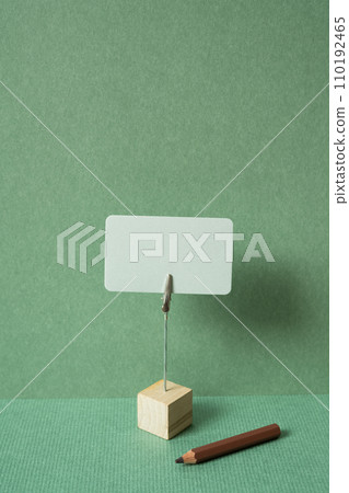 Memo pad with holder and colored pencil on desk. green wall background. copy space 110192465
