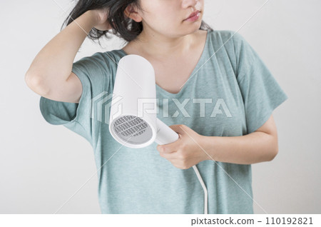 young woman using a hair dryer young woman using a hair dryer 110192821