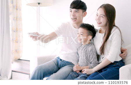 Relaxed Asian family watching TV together at home Relaxed Asian family watching TV together at home 110193576