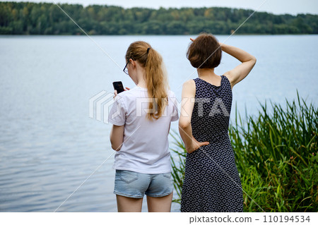 Mother and daughter by the shore of the lake Mother and daughter by the shore of the lake 110194534
