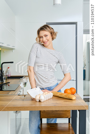 Happy young woman in the kitchen behind the tabletop 110194537