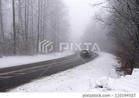 Cars in the fog. Bad winter weather and dangerous automobile traffic on the road. Light vehicles in foggy day. 110194587
