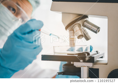 Female researchers are experimenting with pipette dropping a sample into a test tube in an experiment research in laboratory... 110195527