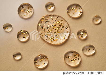 Serum with 24K Gold particles. Drops on a beige background. Serum with 24K Gold particles. Drops on a beige background. 110197096
