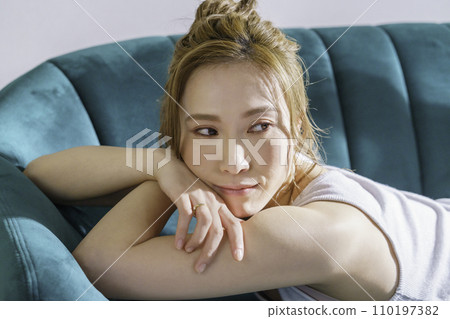 一位年輕的棕髮女子躺在沙發上的半身像 110197382