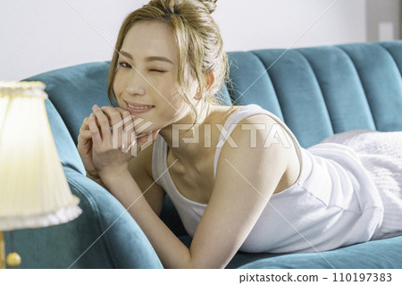 一位年輕的棕髮女子躺在沙發上的半身像 一位年輕的棕髮女子躺在沙發上的半身像 110197383