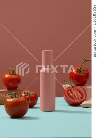 Beauty skin care bottle decorated with tomatoes and stones on blue surface. Natural beauty blank label for branding mock-up concept Beauty skin care bottle decorated with tomatoes and stones on blue surface. Natural beauty blank label for branding mock-up concept 110198658