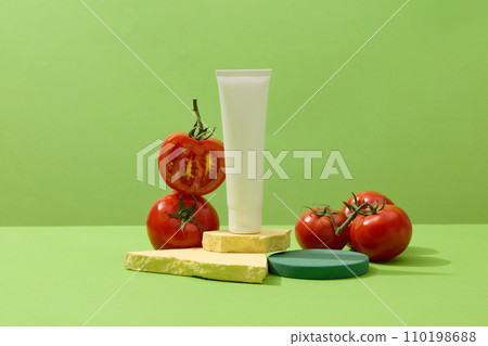 Blank label beauty tube standing on broken stones, decorated with red tomatoes. Applying tomato on the face can minimize and prevent acne 110198688