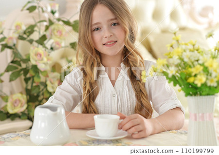 Smiling little girl holding big cup of tea 110199799