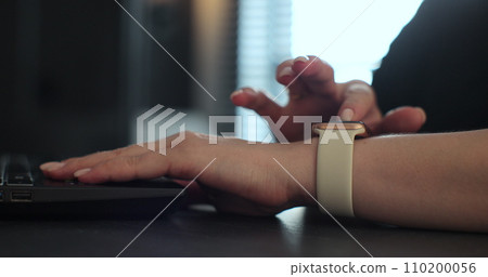 Woman browsing notifications on modern smart watches while working. Young woman using smart watch. Woman browsing notifications on modern smart watches while working. Young woman using smart watch. 110200056