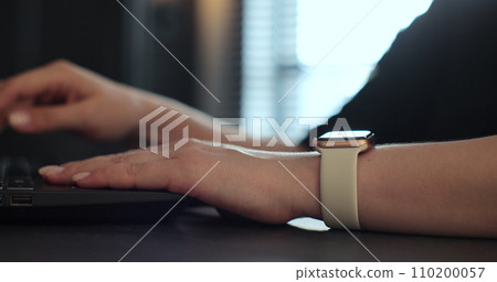 Woman browsing notifications on modern smart watches while working. Young woman using smart watch. Woman browsing notifications on modern smart watches while working. Young woman using smart watch. 110200057