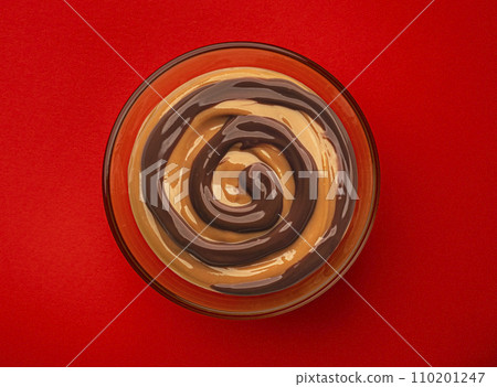 Caramel sauce swirl and chocolate cream mix on red background, top view 110201247