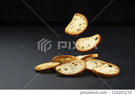 Falling bruschetta crackers, round bread croutons isolated on black background with copy space, full depth of field Falling bruschetta crackers, round bread croutons isolated on black background with copy space, full depth of field 110201250