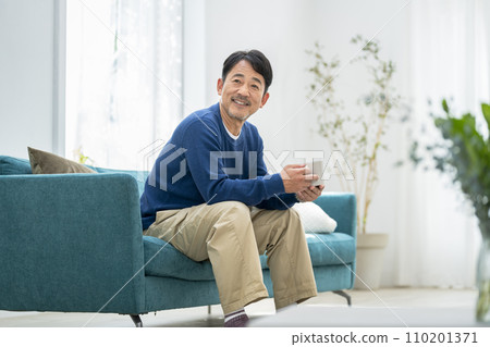 A man in his mid-50s relaxing at home 110201371
